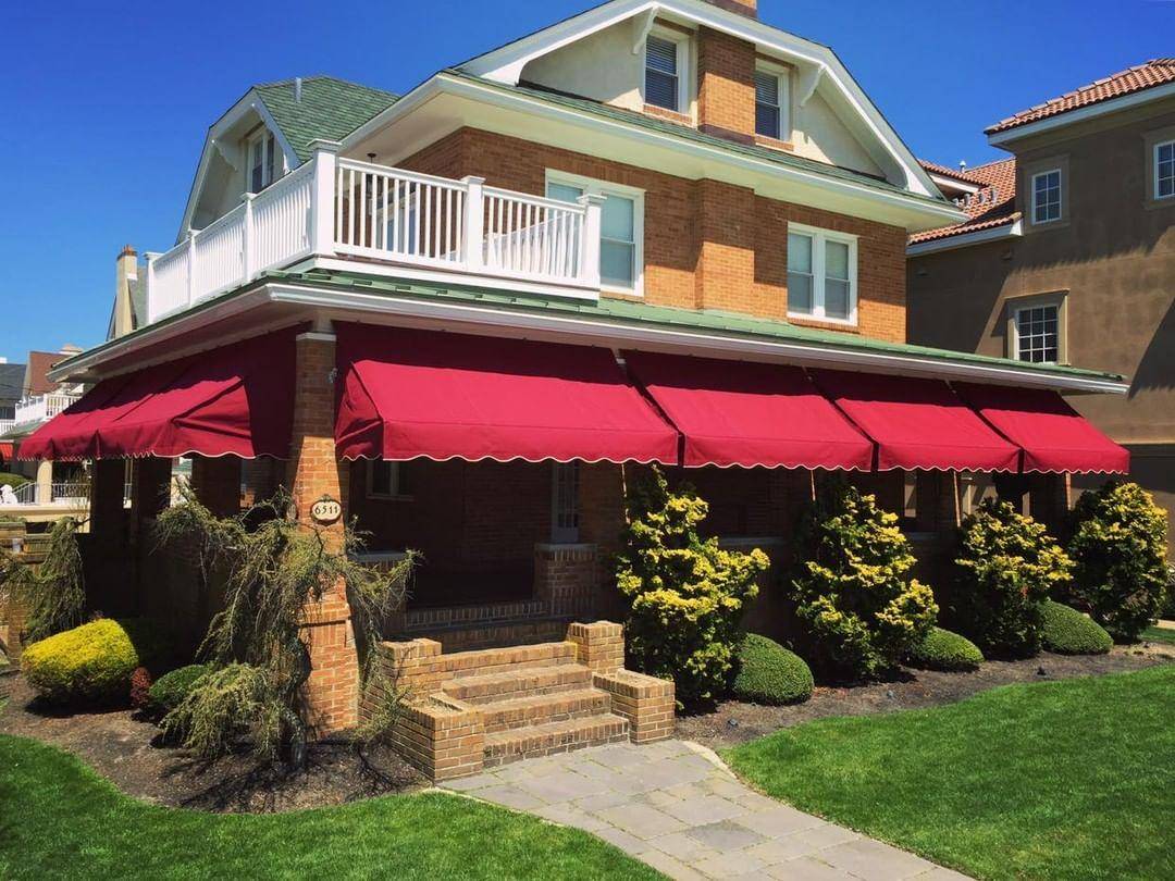 A home with red traditional fabric awnings made by Berges Trenton Awning.