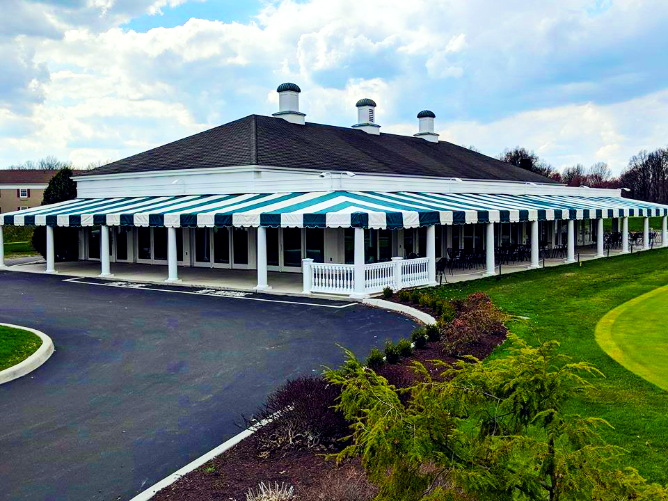 A building with a wrap around green and white striped awning made out of Top Gun FR awning fabric.