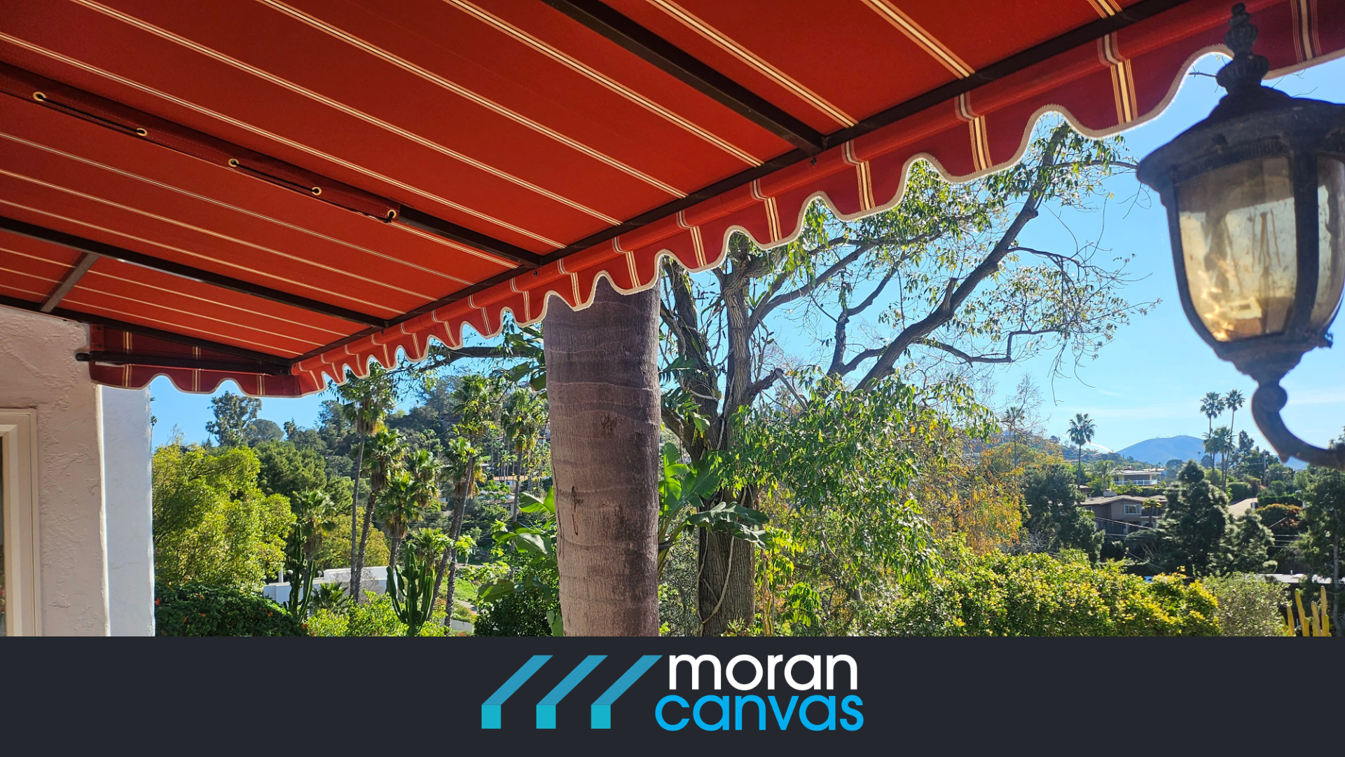 Red and white striped awning over a lush garden with palm trees; classic lantern beside it; bright blue sky; text "moran canvas" at the bottom.